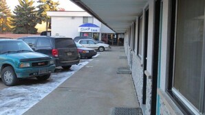 A motel with a covered parking area, several parked cars, and a visible 'Sleep Inn' sign.