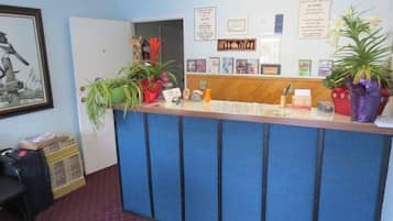 Una reception con un banco blu, piante in vaso, certificati incorniciati e un quadro appeso al muro.