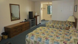 A hotel room with two beds, a TV, a dresser, and a mirror.