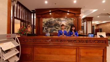 A reception desk with two staff members, a wooden panel design, a large mural, and a BYD self-service kiosk.