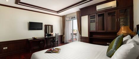 A hotel room with a large bed, a desk with a computer, a television, and a wardrobe.
