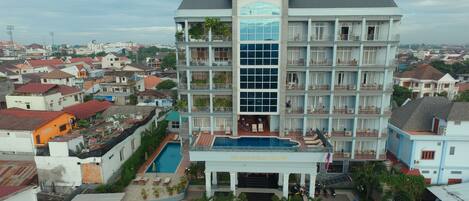 A multi-story hotel with a swimming pool, surrounded by residential buildings.