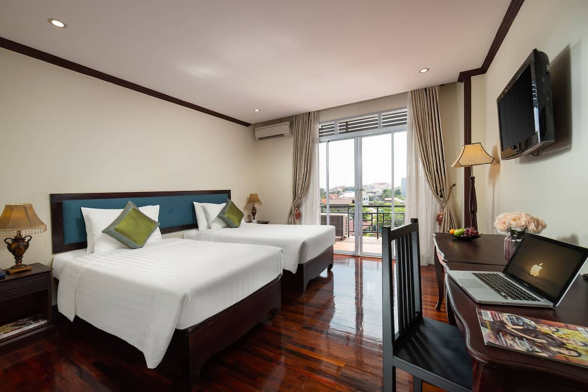 Une chambre d’hôtel avec deux lits, un bureau avec un ordinateur portable, une télévision et un balcon avec vue.
