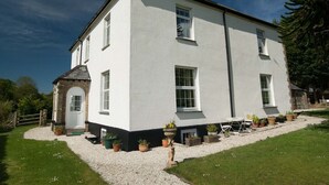 A two-story white building with a small stone entrance, multiple windows, and a gravel driveway with potted plants. - Poole Farm (Launceston)