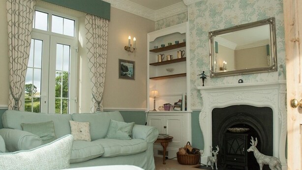 A cozy living room with a fireplace, a sofa, and a bookshelf. - Poole Farm (Launceston)