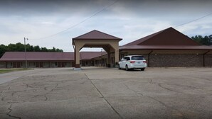 A building with a covered entrance and a parking area. - Claridge Inn (Waynesboro)