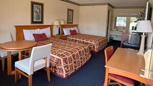 A hotel room with two beds, a dining table, chairs, a small table with a lamp, and a television. - Claridge Inn (Waynesboro)