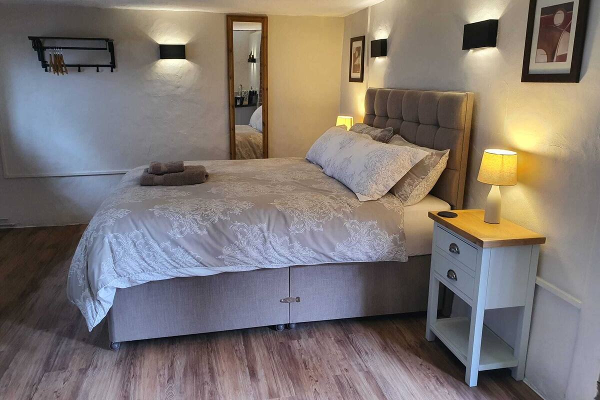 A bedroom with a bed, bedside tables, a mirror, and wall-mounted lights.