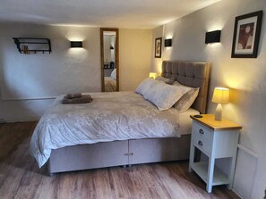 Ein Schlafzimmer mit Bett, Nachttischen, einem Spiegel und Wandleuchten.
