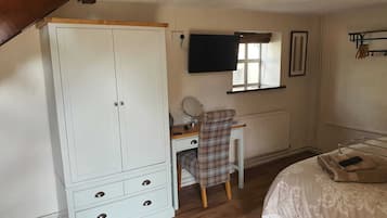 A bedroom with a large wardrobe, a desk with a chair, a bed, a window, and a radiator.