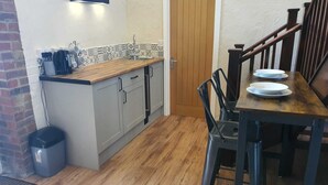 A compact kitchen with a wooden countertop, grey cabinets, and a tiled backsplash. - The Lower Bell (Aylesford)