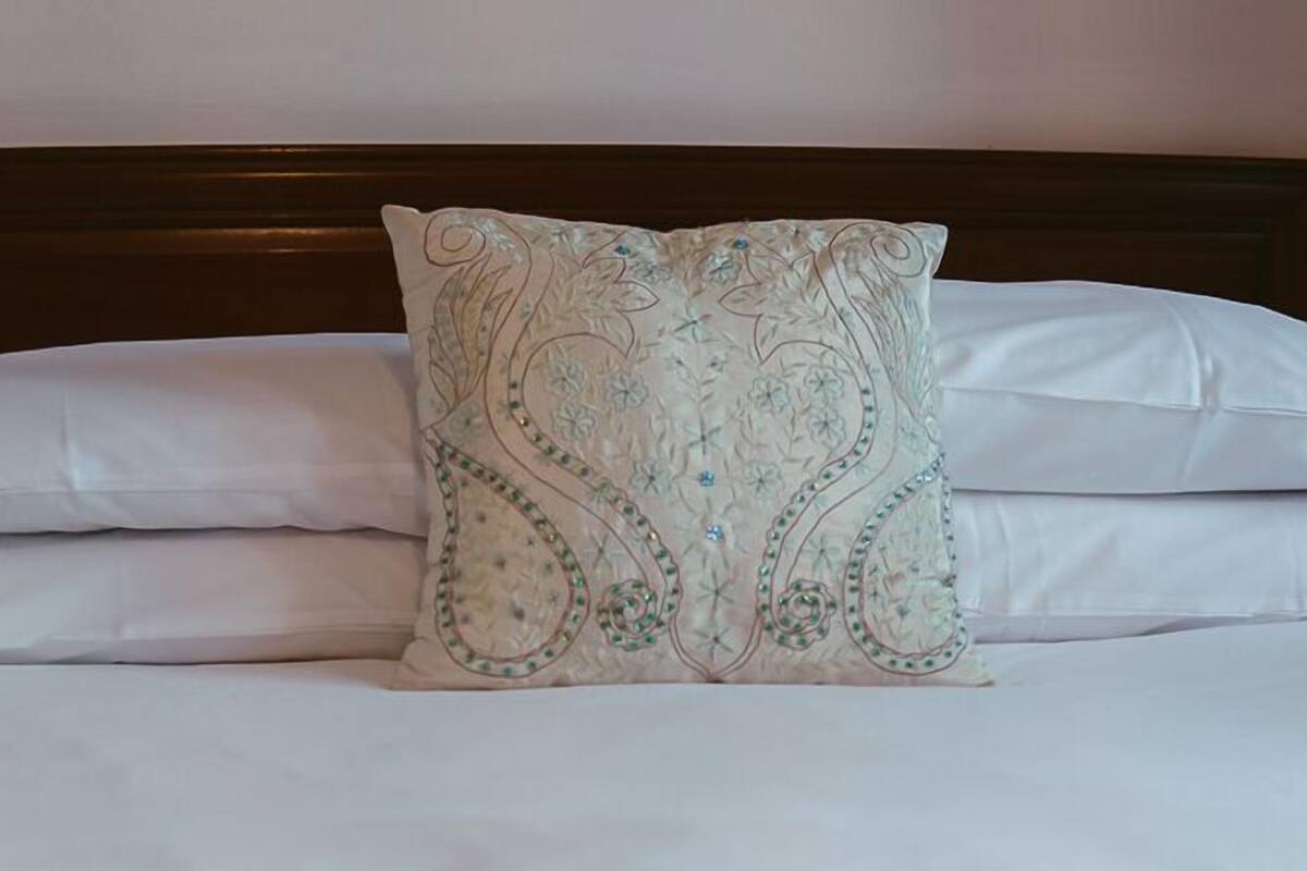 A neatly made bed with a decorative pillow and a folded blanket.