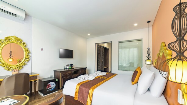A hotel room with a large bed, a desk with a computer, a television, and a minibar. - Xaysomboun Hotel & Spa (Vientiane)