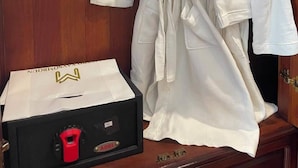 A wooden wardrobe with two white robes hanging on hangers.