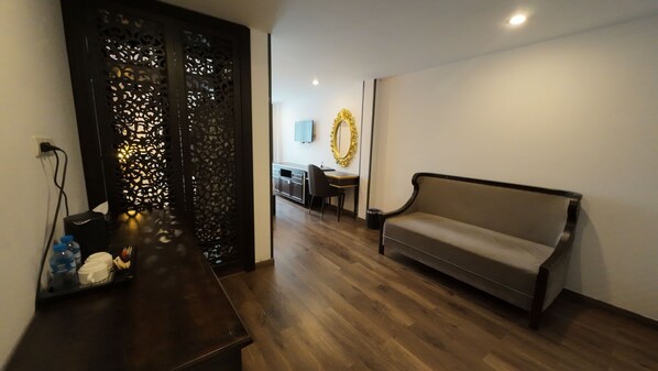 A modern living room with a sofa, a wooden coffee table, and a decorative screen.