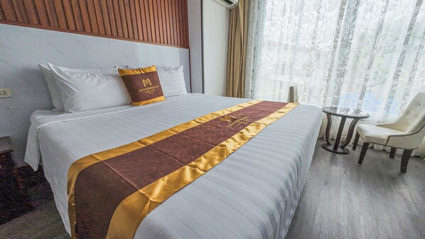 Una habitación de hotel con una cama grande, una mesita redonda y una silla.