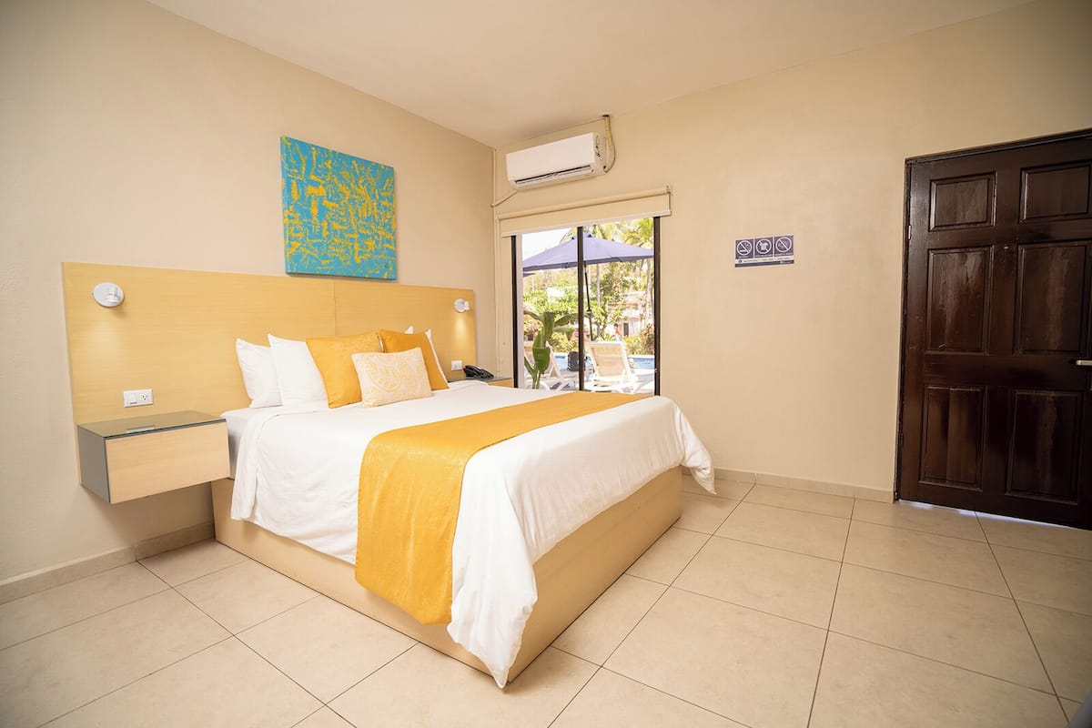 Habitación de hotel con cama, mesita de noche y ventana con vistas al exterior.
