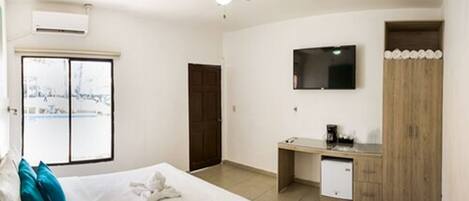 A bedroom with a bed, a desk, a television, and a wardrobe.