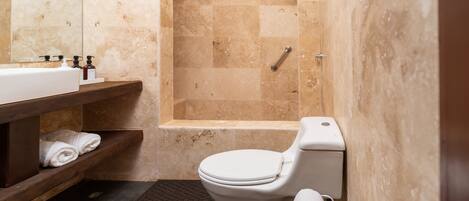 A bathroom with a toilet, a sink, and a shower area.