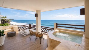 A covered outdoor area with a wooden deck, a hot tub, and a view of the ocean.