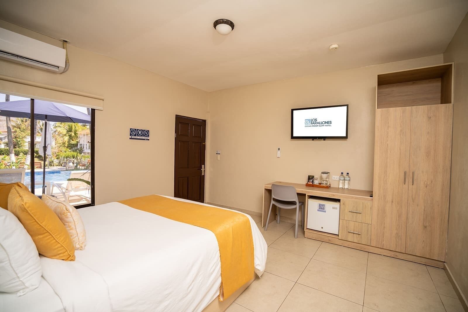 A hotel room with a bed, a desk, a TV, and a wardrobe.