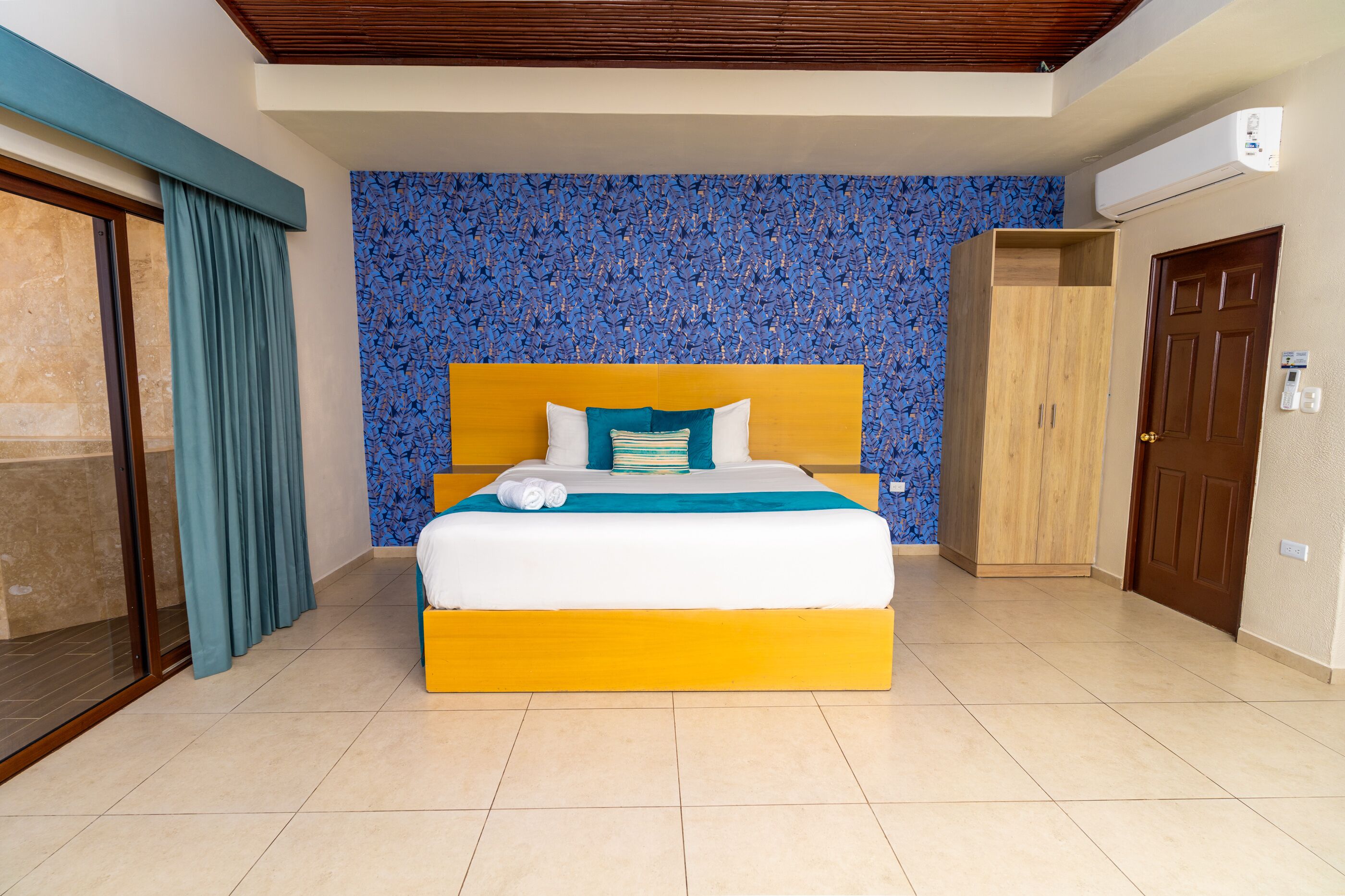 Una habitación de hotel con una cama grande, un armario y una puerta corrediza de vidrio.