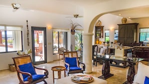A spacious living area with a white sofa, two blue chairs, a coffee table, and a dining table. - Royal Palms by Bric (Playa del Carmen)