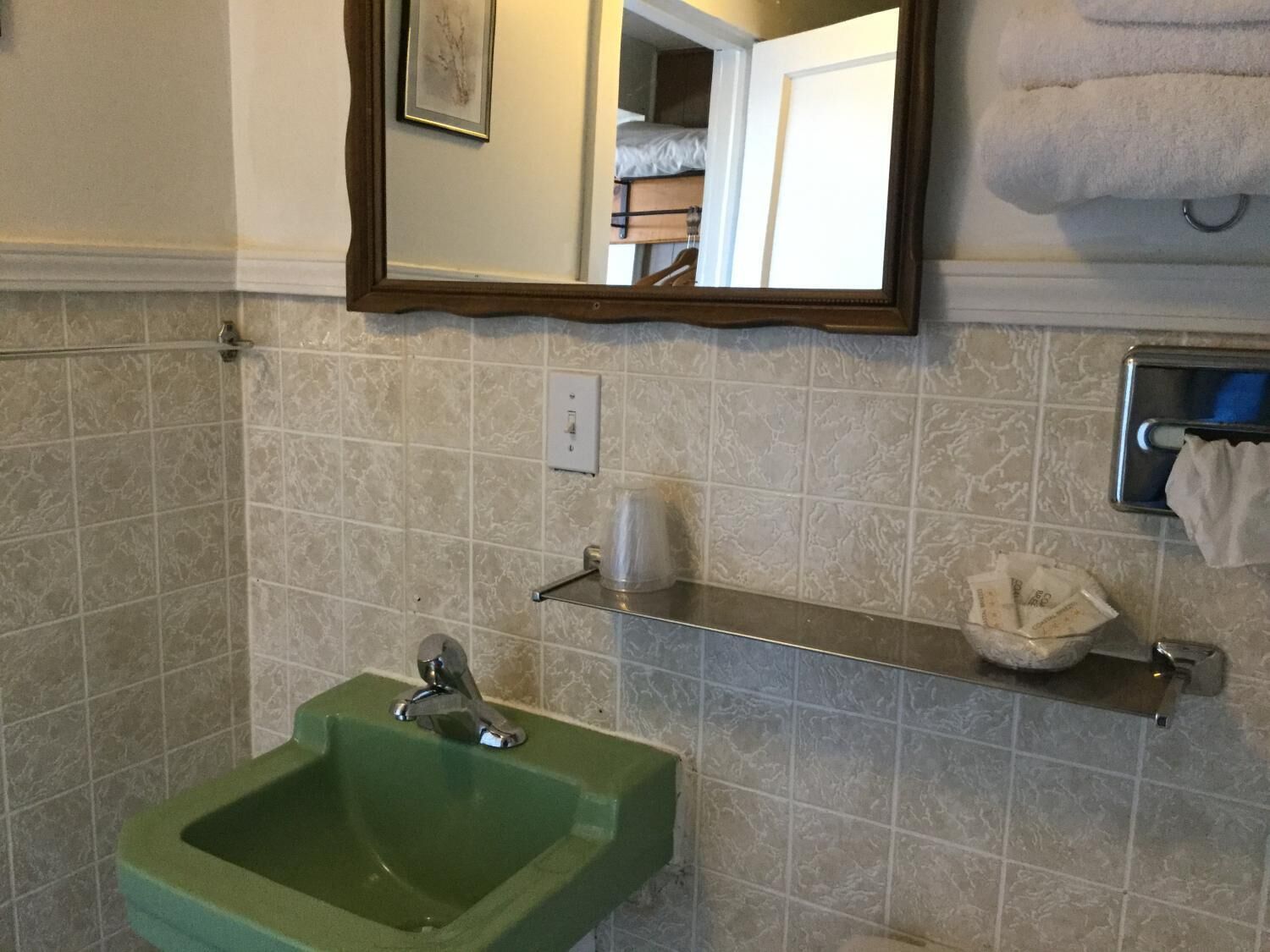 Casa de banho com uma pia verde, um espelho e um porta-toalhas.