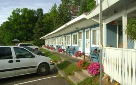 A row of single-story buildings with a row of parked cars in front.