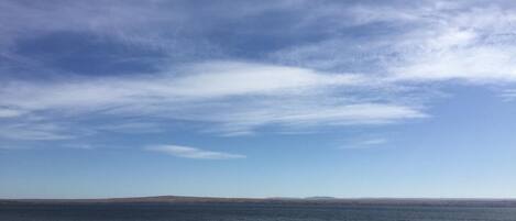 A coastal road with a view of the sea and distant hills.