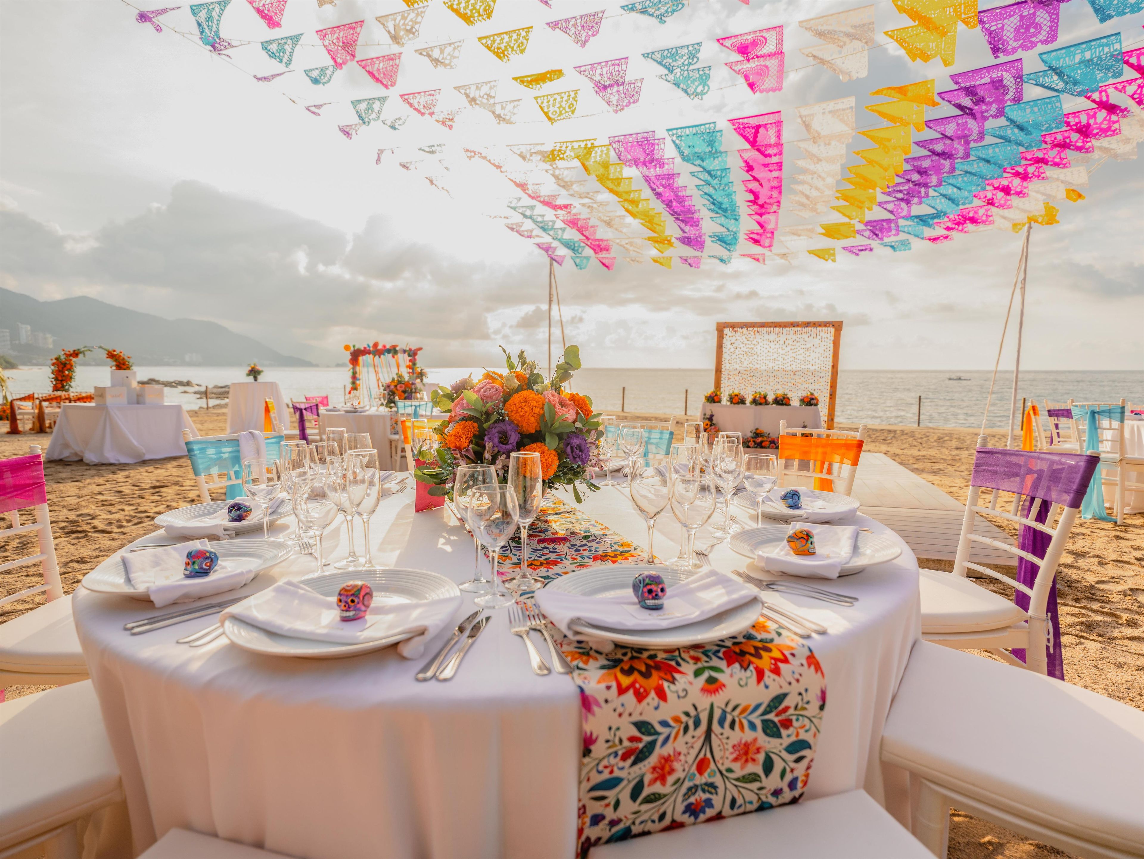 A beachside dining setup with tables, chairs, and a view of the sea.