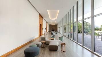 A modern hotel lobby with a long corridor, large windows, and a variety of seating options.