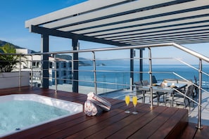 Enjoy breathtaking ocean views from this expansive deck, featuring a hot tub, bar, and comfortable seating.