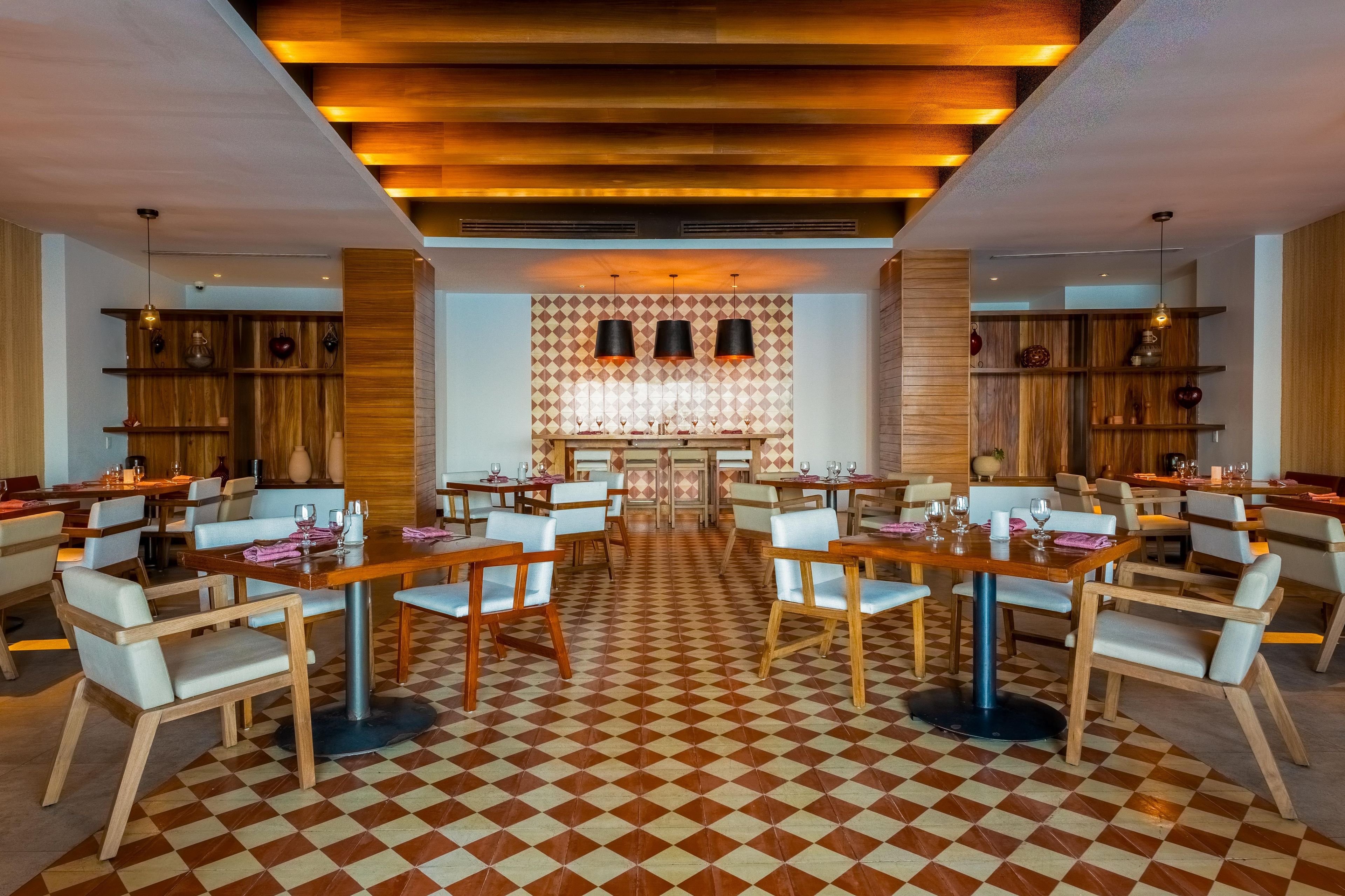 A hotel lobby with checkered flooring, wooden furniture, and a central bar area.