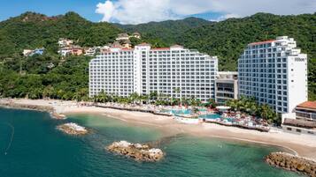 A beachfront hotel with multiple high-rise buildings, a swimming pool, and a beach area.