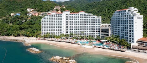 A beachfront hotel with multiple high-rise buildings, a swimming pool, and a beach area.