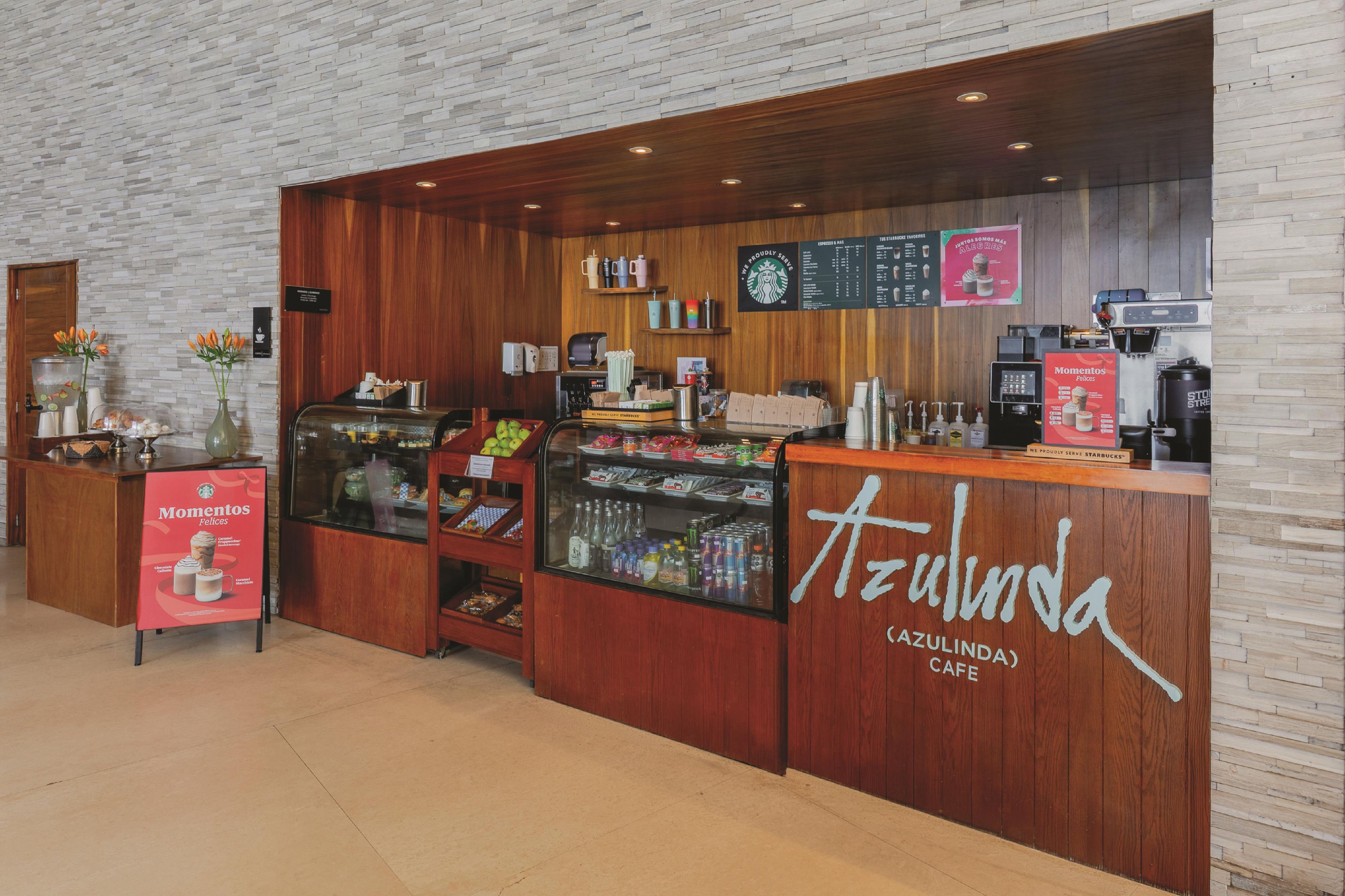 A Starbucks cafe with a wooden counter, a glass display case, and a menu board.