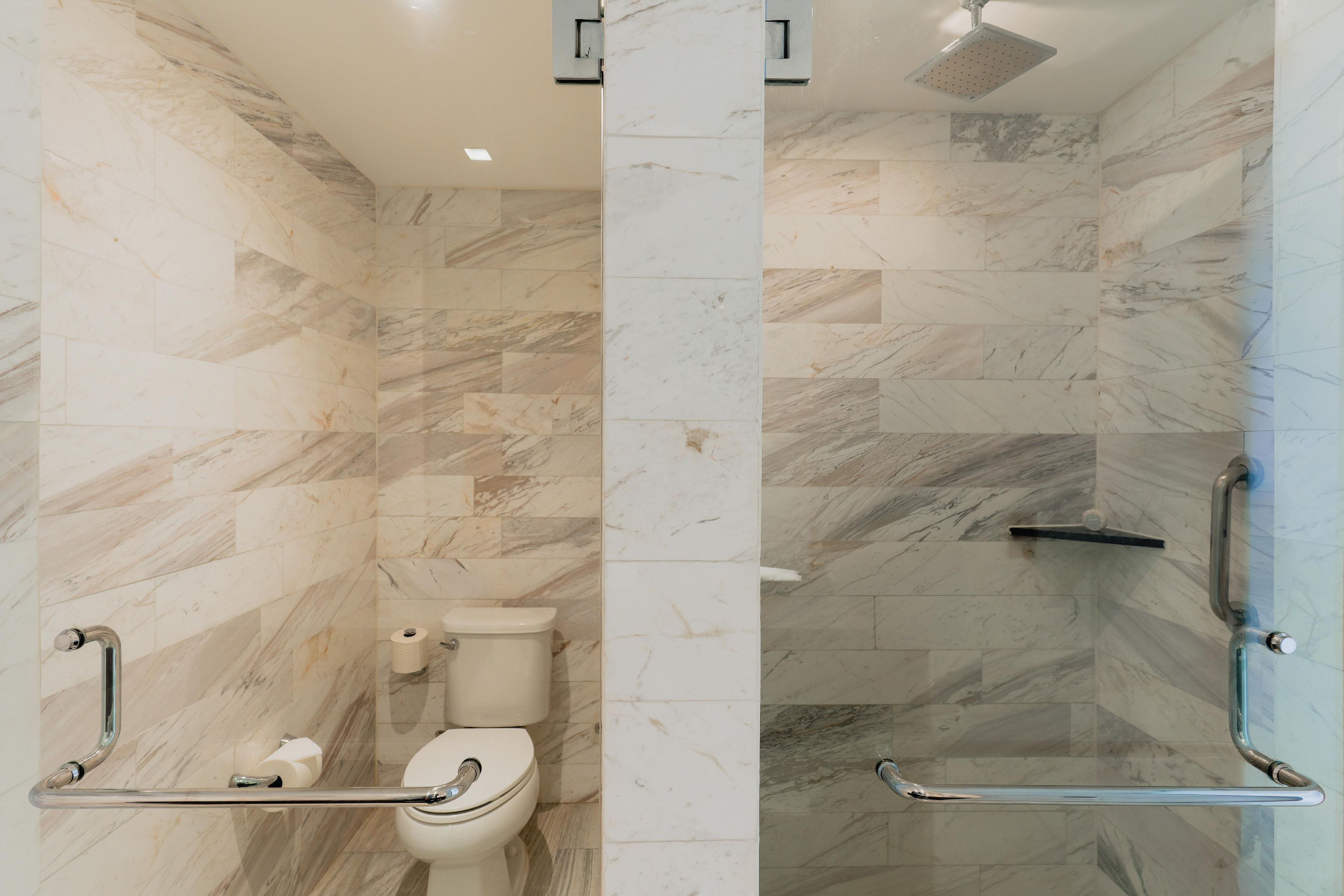 Une salle de bain équipée de toilettes, d’une douche et d’une barre d’appui.