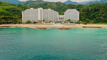 Un hôtel à étages, situé en bord de plage, avec une chaîne de montagnes en arrière-plan.