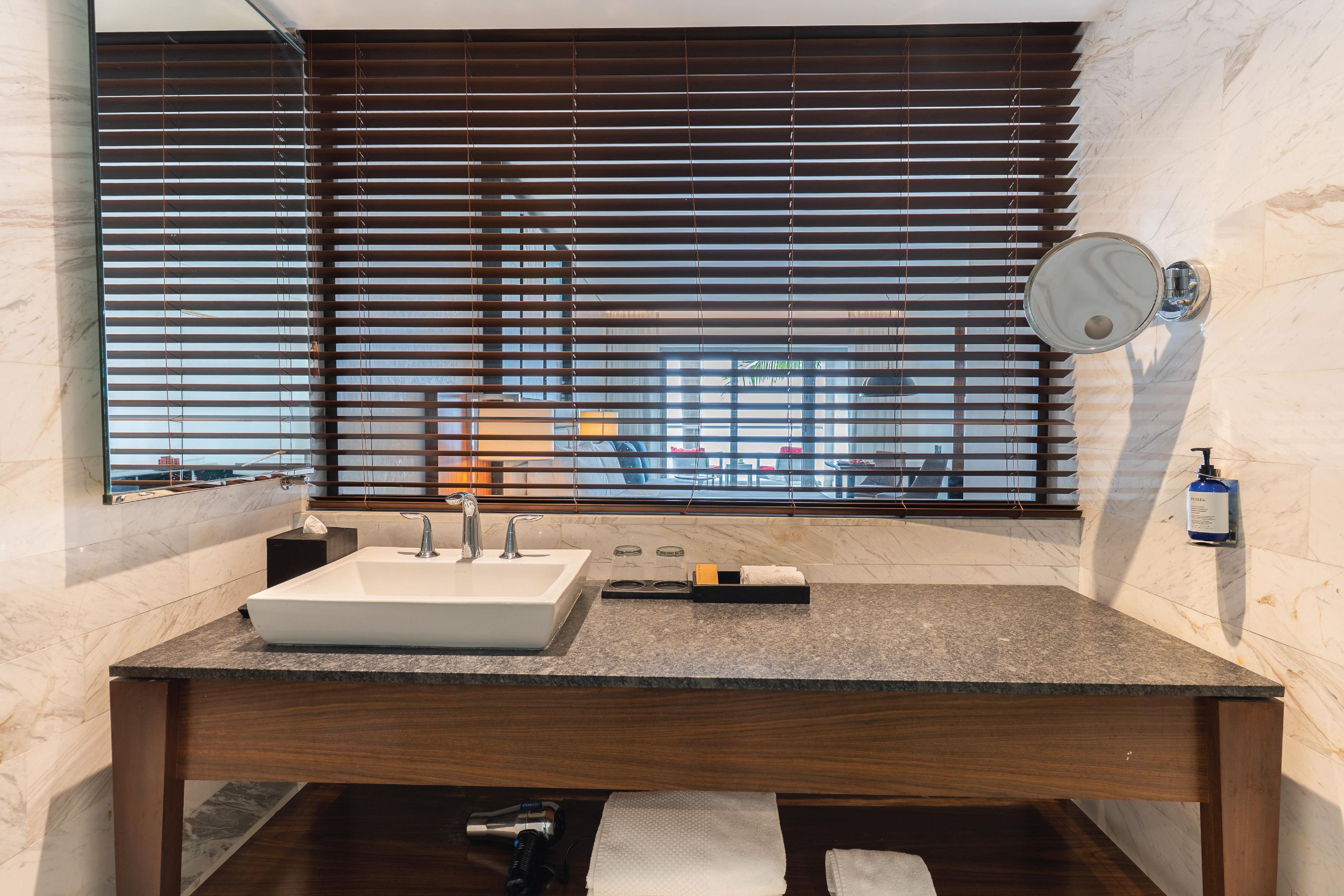 A bathroom with a large window, a sink, and a mirror.