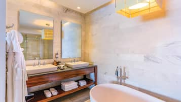 A modern bathroom with two sinks, a large bathtub, wooden vanity, and a mirror.