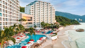 Un hotel con múltiples piscinas, zonas de descanso en la playa y vista al océano.