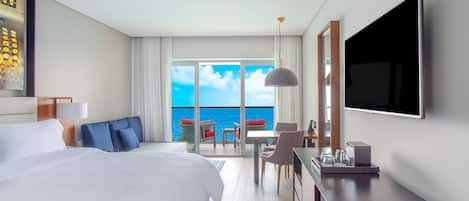 Habitación de hotel con una cama grande, escritorio, televisor y balcón con vistas al mar.