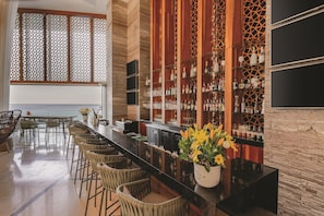 A bar area with a long counter, wicker chairs, and a view of the ocean.