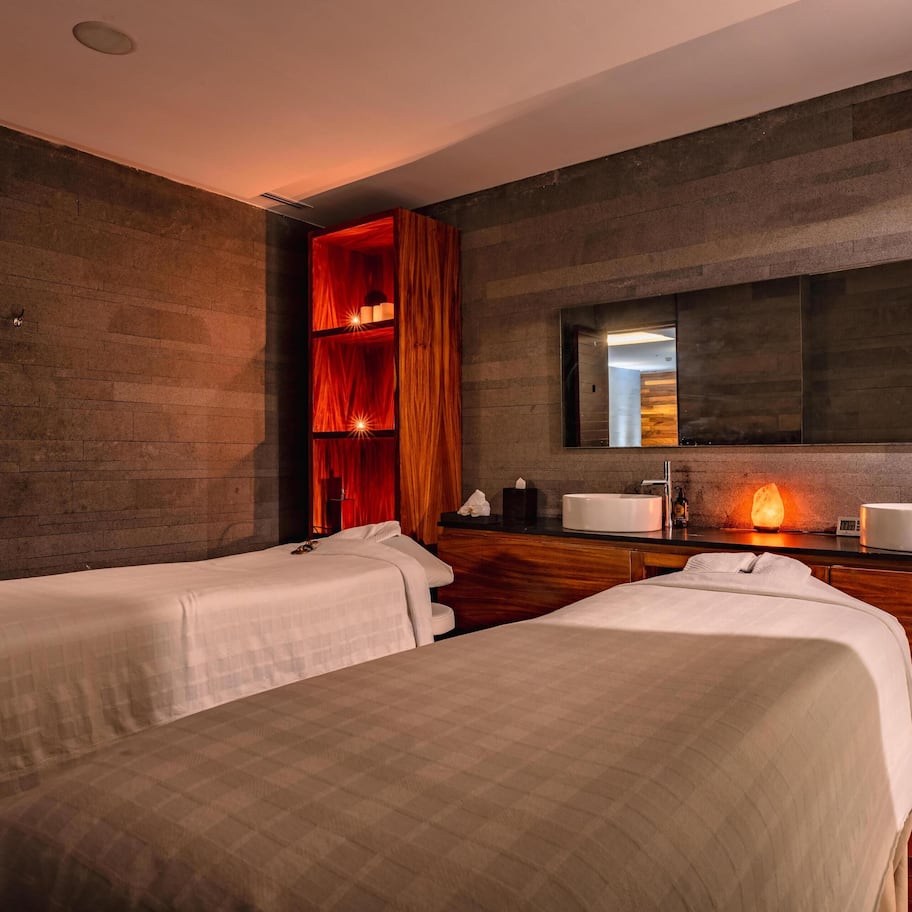 A hotel room with two beds, a wooden vanity with a mirror, and a modern design.