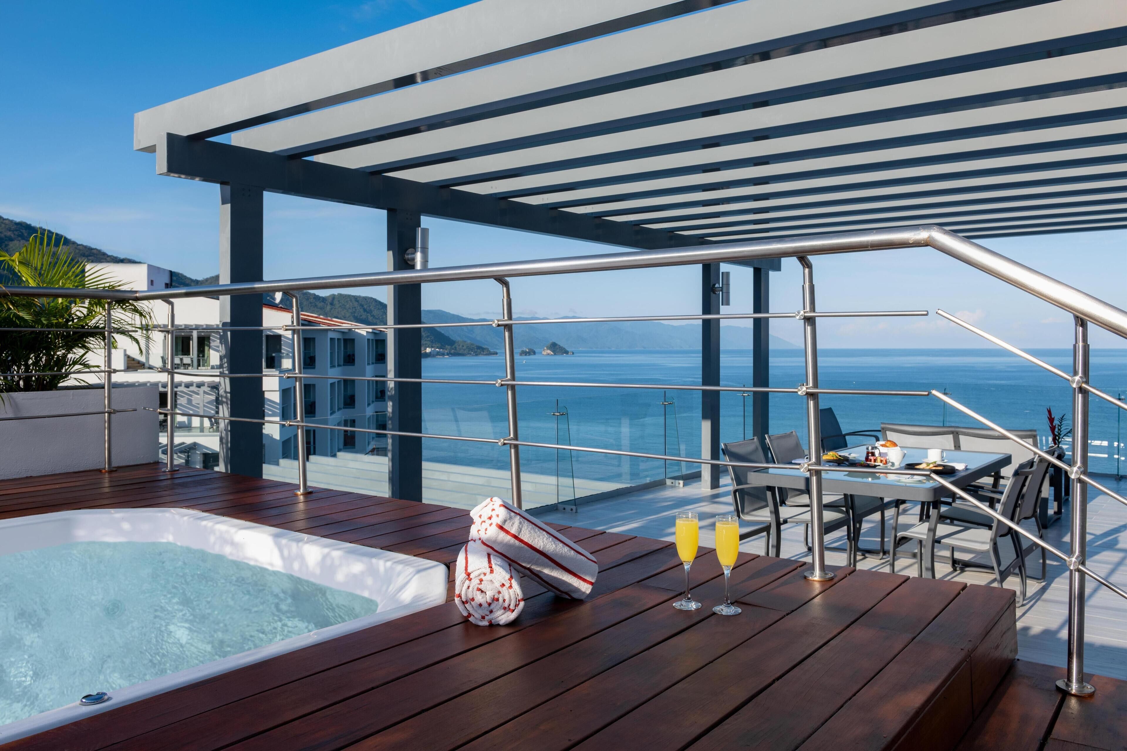 Una terraza en la azotea con jacuzzi, zona de comedor y vistas al mar.