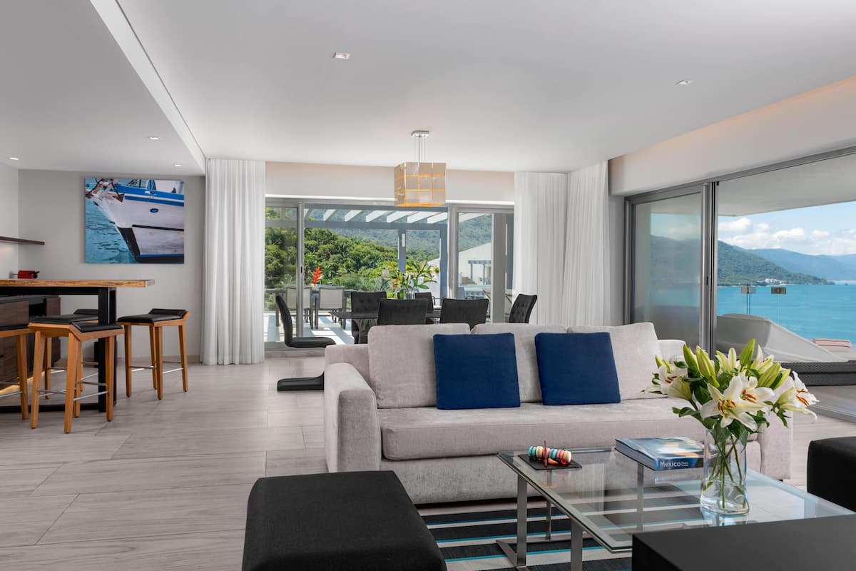 A modern living room with a sofa, coffee table, and a view of the sea.