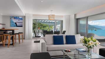 A modern living room with a sofa, coffee table, and a view of the sea.