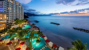 Un resort con un edificio grande, una piscina y vistas al mar.