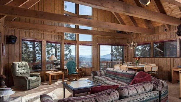 A spacious wooden cabin with large windows, a cozy seating area, and a dining table. - Pinnacle View (Truckee)